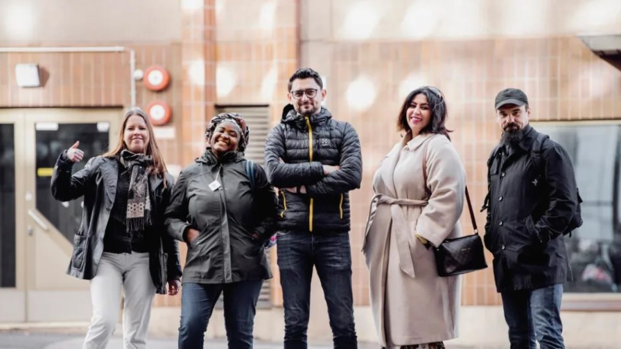 Kuvassa viisi eri maista muuttanut ihmistä seisovat yhdessä kuvassa.